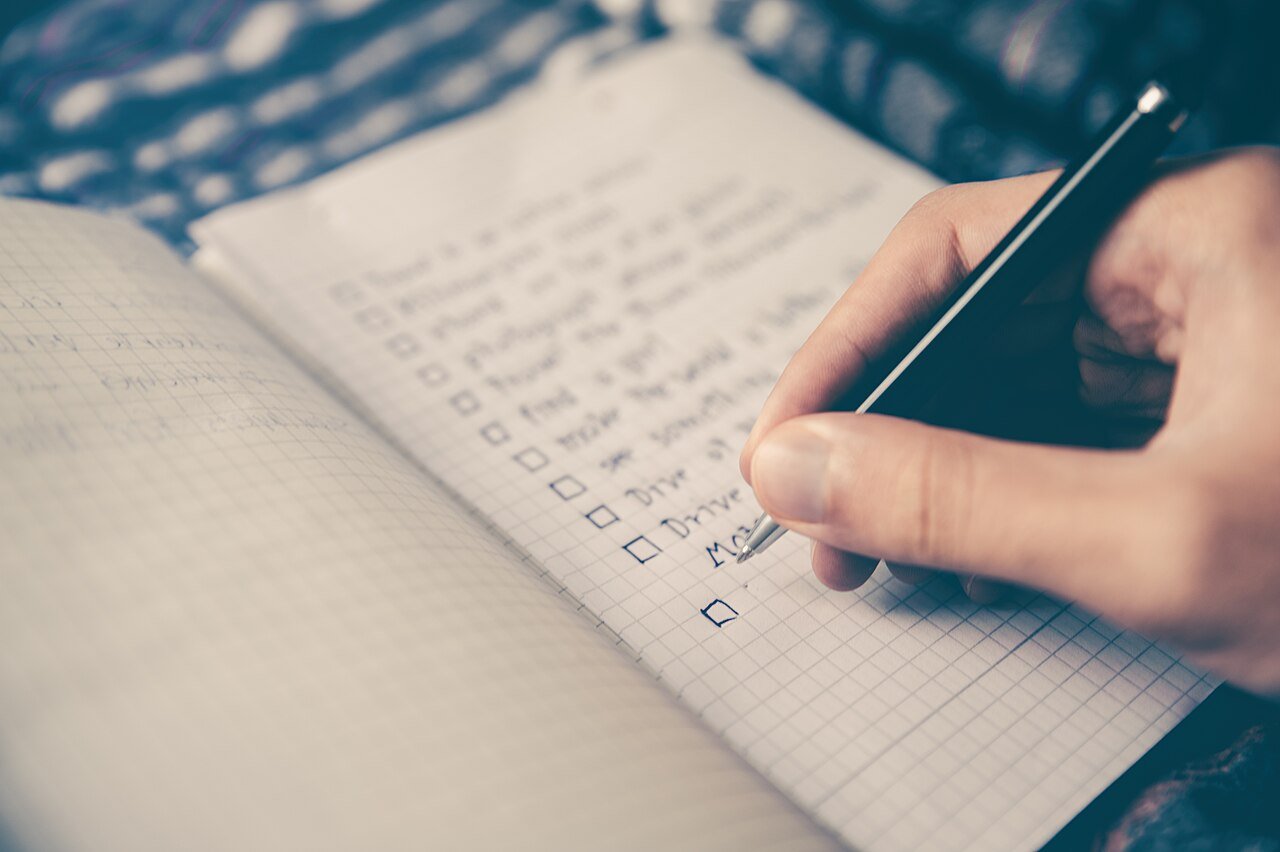 Hand ticking off a checklist in a notebook with a pen