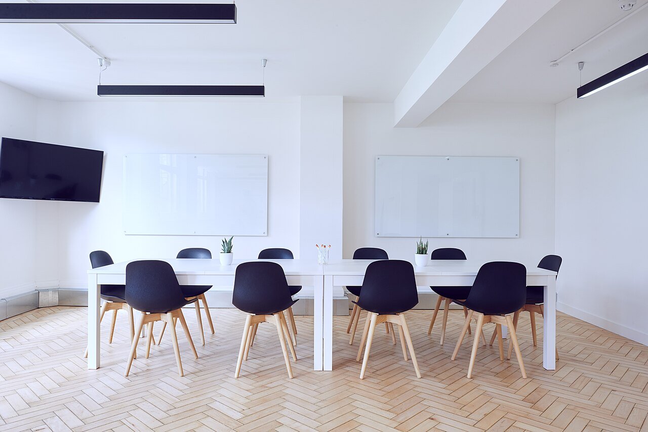 Empty bright conference room with a long table, chairs and whiteboards