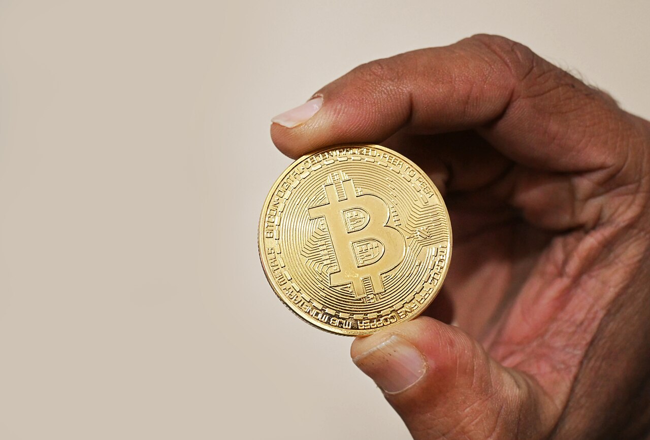 Hand holding a gold-colored cryptocurrency coin